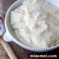 close up of gluten-free chicken soup in a white bowl with wooden spoon next to it