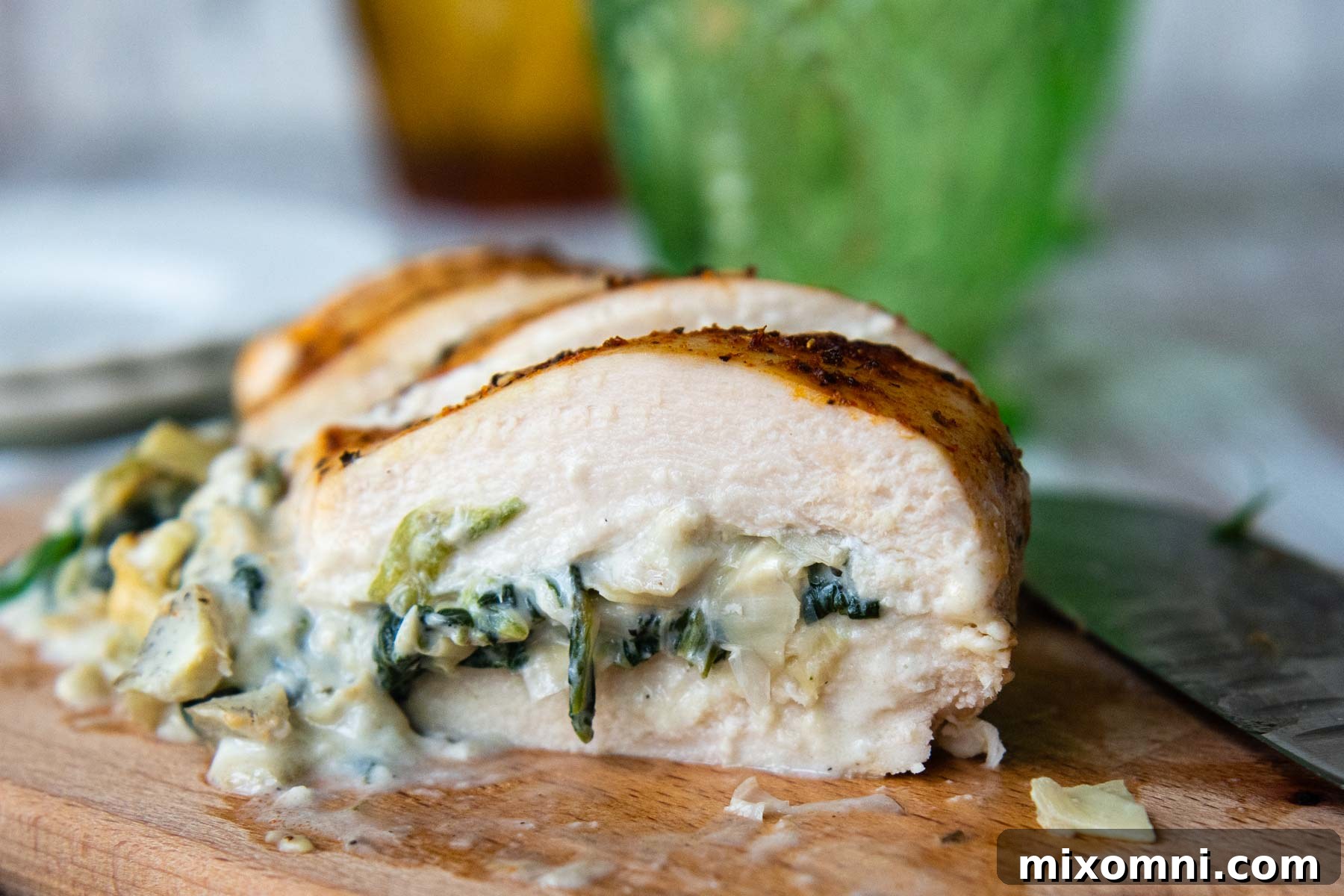 Close-up of the interior of a baked spinach artichoke stuffed chicken breast, showing the delicious, creamy, and cheesy filling.