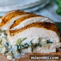 Close-up of perfectly sliced spinach artichoke stuffed chicken on a wooden cutting board, showcasing the delicious filling.