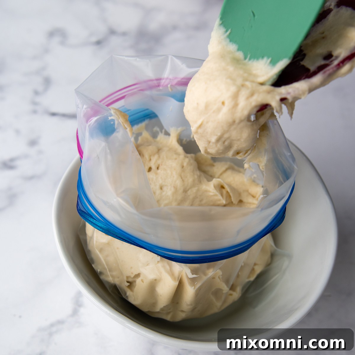 Demonstration of scooping the breadstick dough into a Ziploc bag positioned in a bowl.