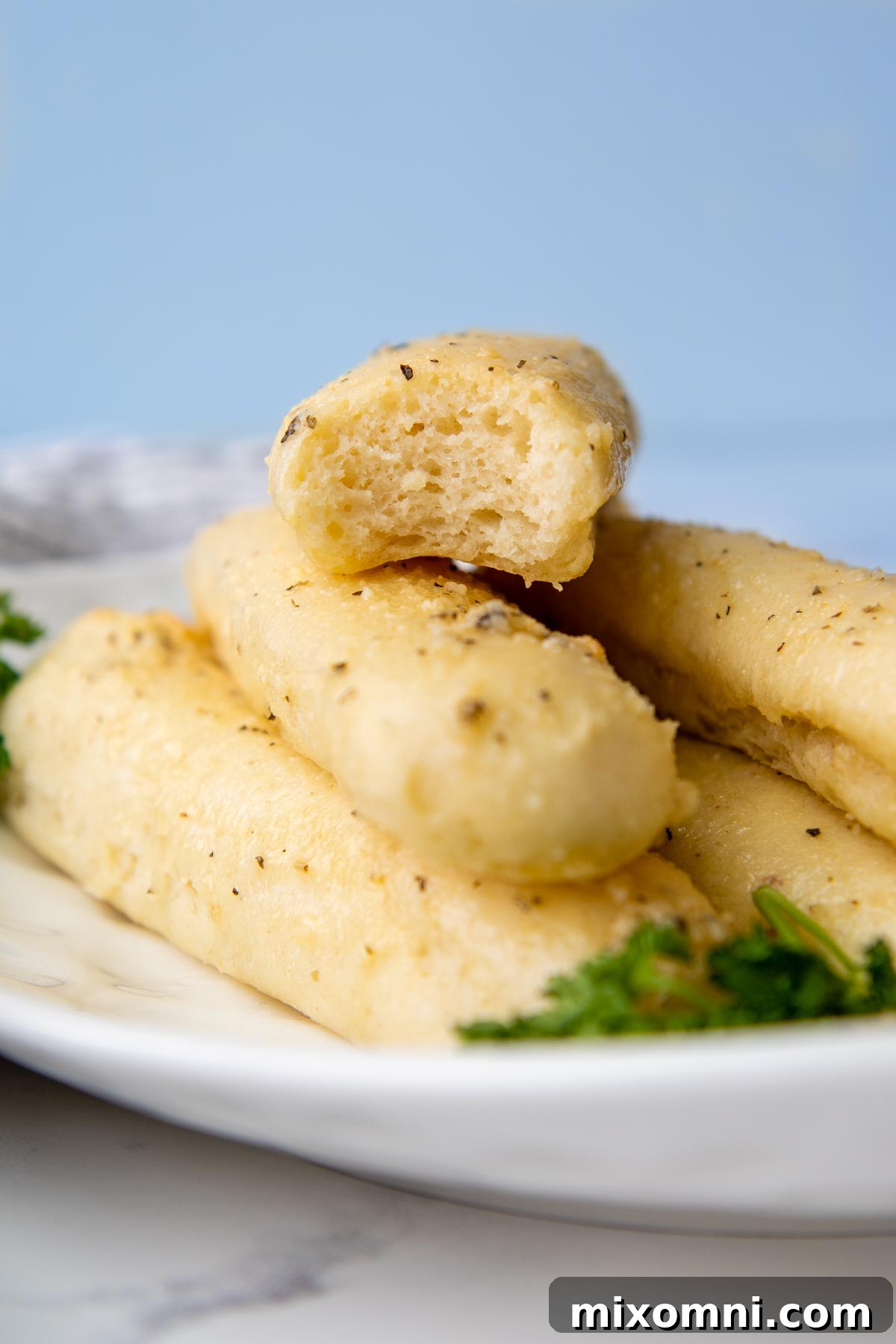 A perfectly baked gluten-free breadstick with a bite taken out, showcasing its soft interior.