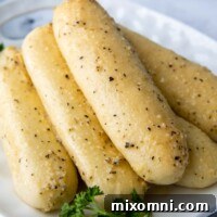 Gluten-free breadsticks stacked on a white plate with parsley garnish