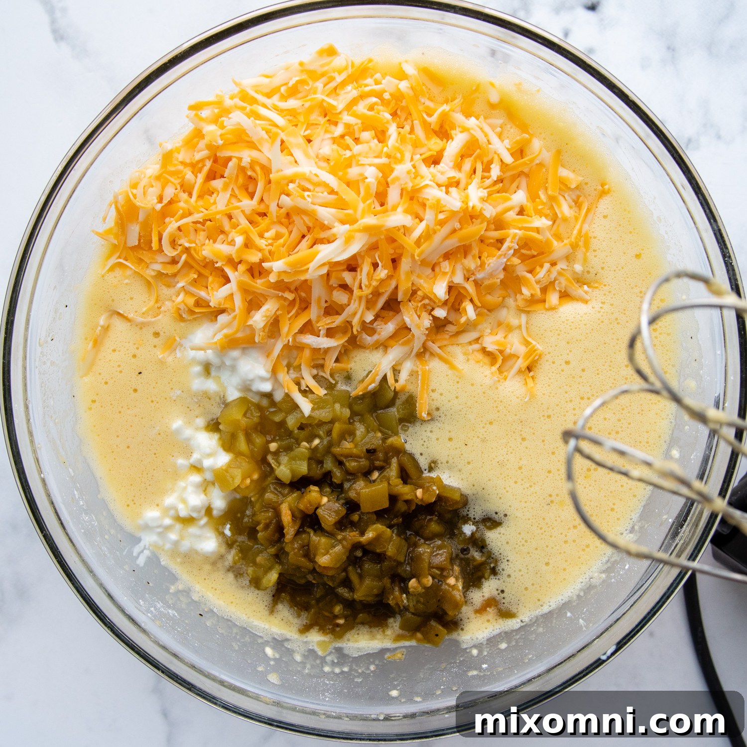 A bowl filled with the vibrant mixture of eggs, green chilies, cottage cheese, and cheese, ready for a final mix.