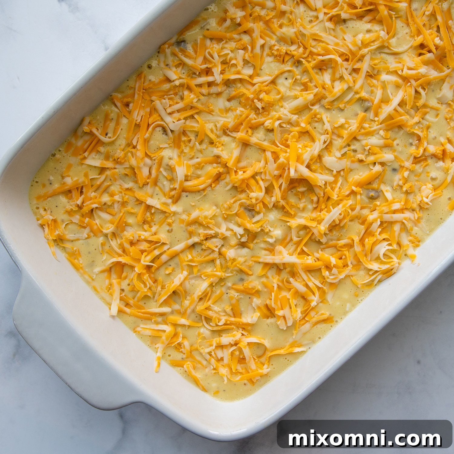 Grated cheese sprinkled over the casserole mixture in a baking dish, ready for baking.