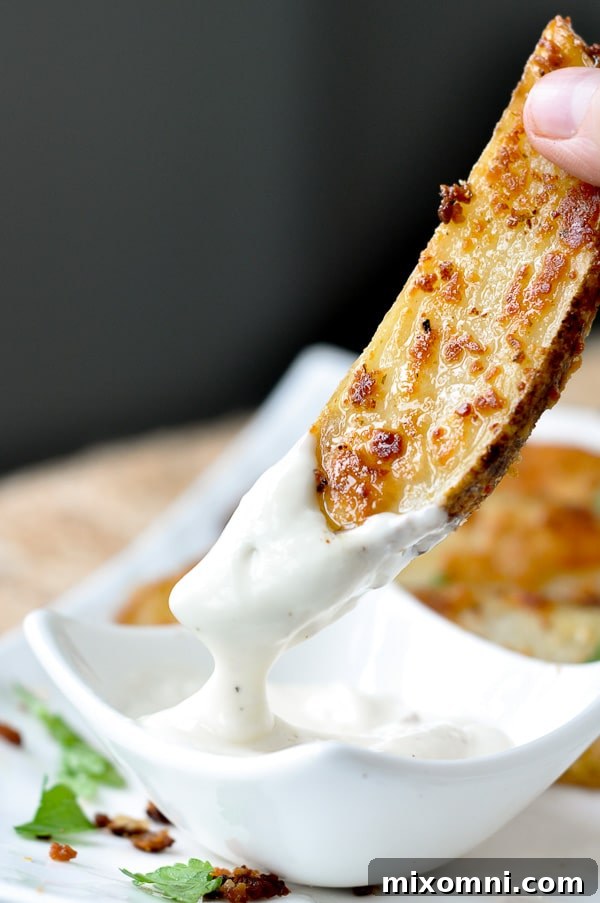 A golden roasted ranch potato wedge being dipped into a creamy ranch dressing.