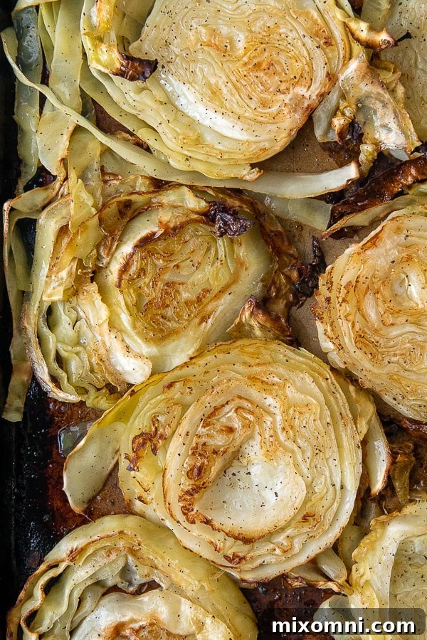 An overhead shot of perfectly roasted cabbage steaks arranged on a baking sheet.