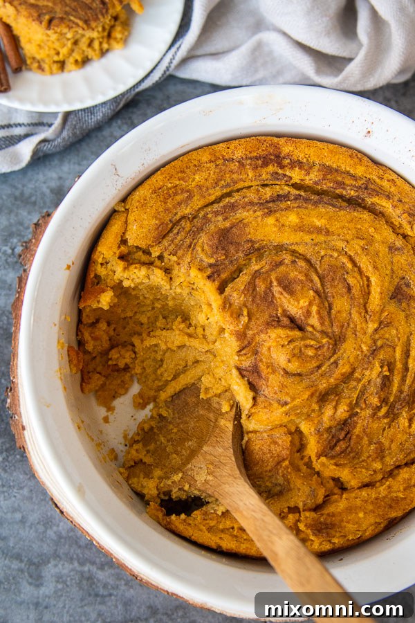 An overhead shot of a sweet potato spoon bread casserole with a scoop taken out, revealing its soft texture.