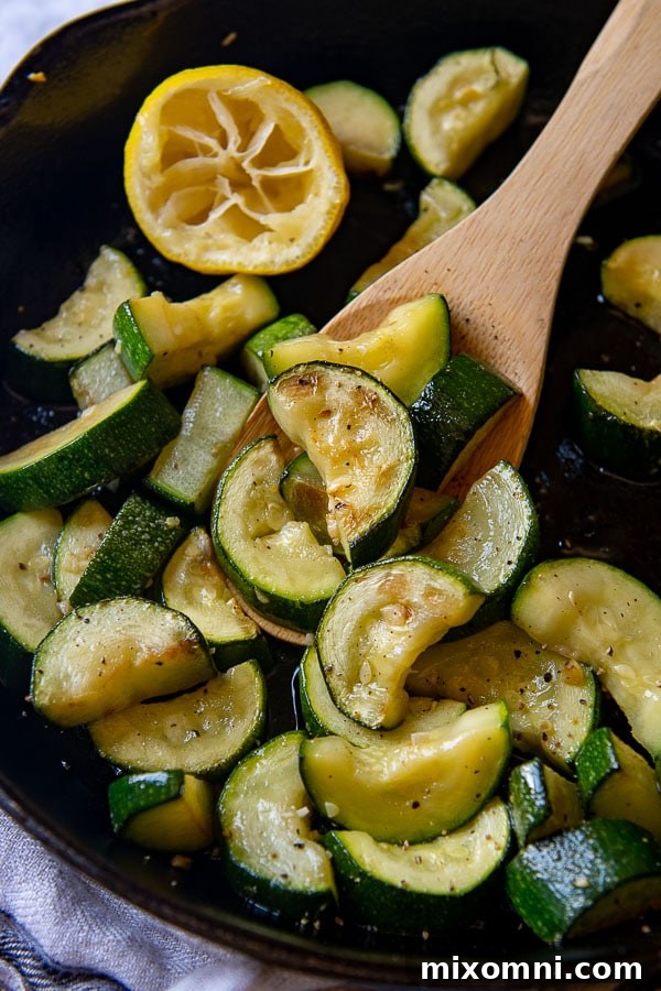 A close-up shot of perfectly cooked zucchini being held by a wooden spoon.