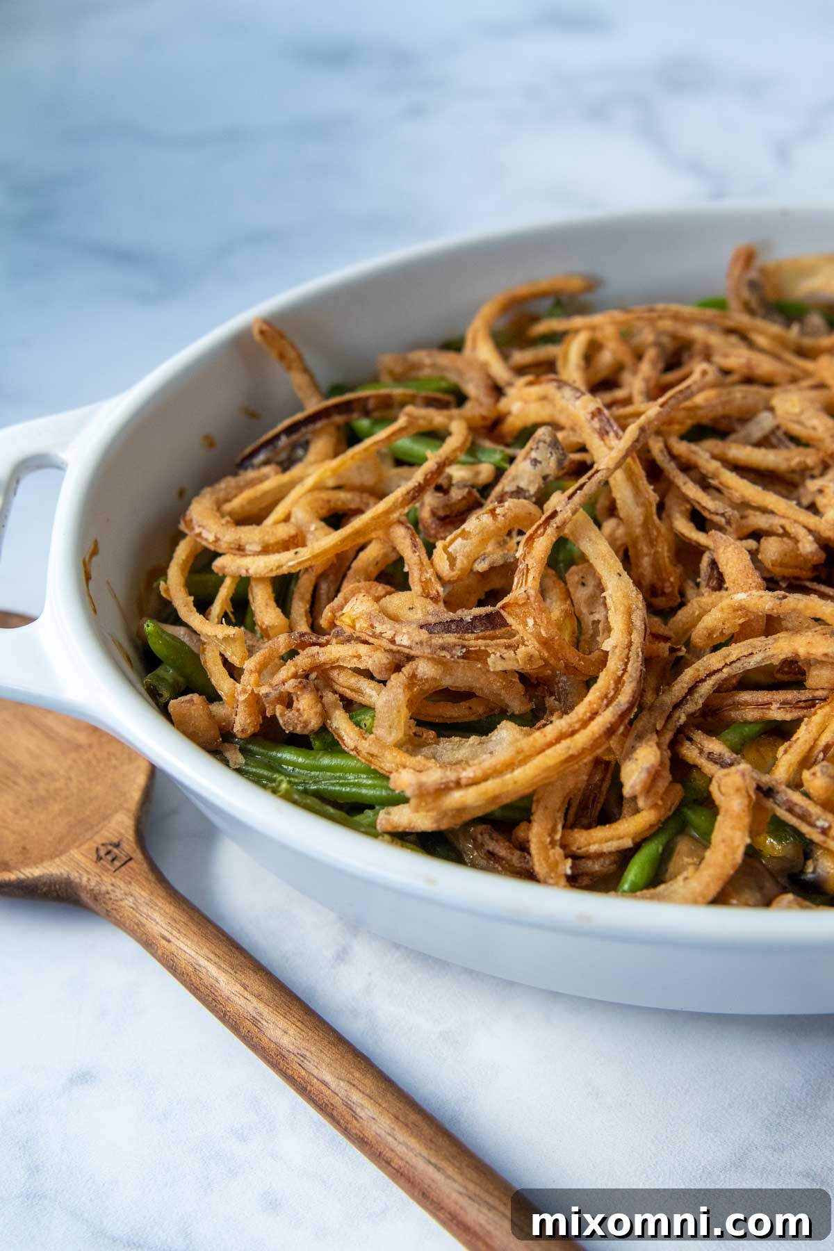 A close-up shot of bubbling gluten-free green bean casserole on a marble surface, ready to serve.