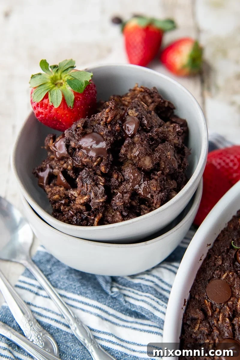 A double-stacked bowl of rich chocolate oatmeal, presented on a vibrant blue striped towel.