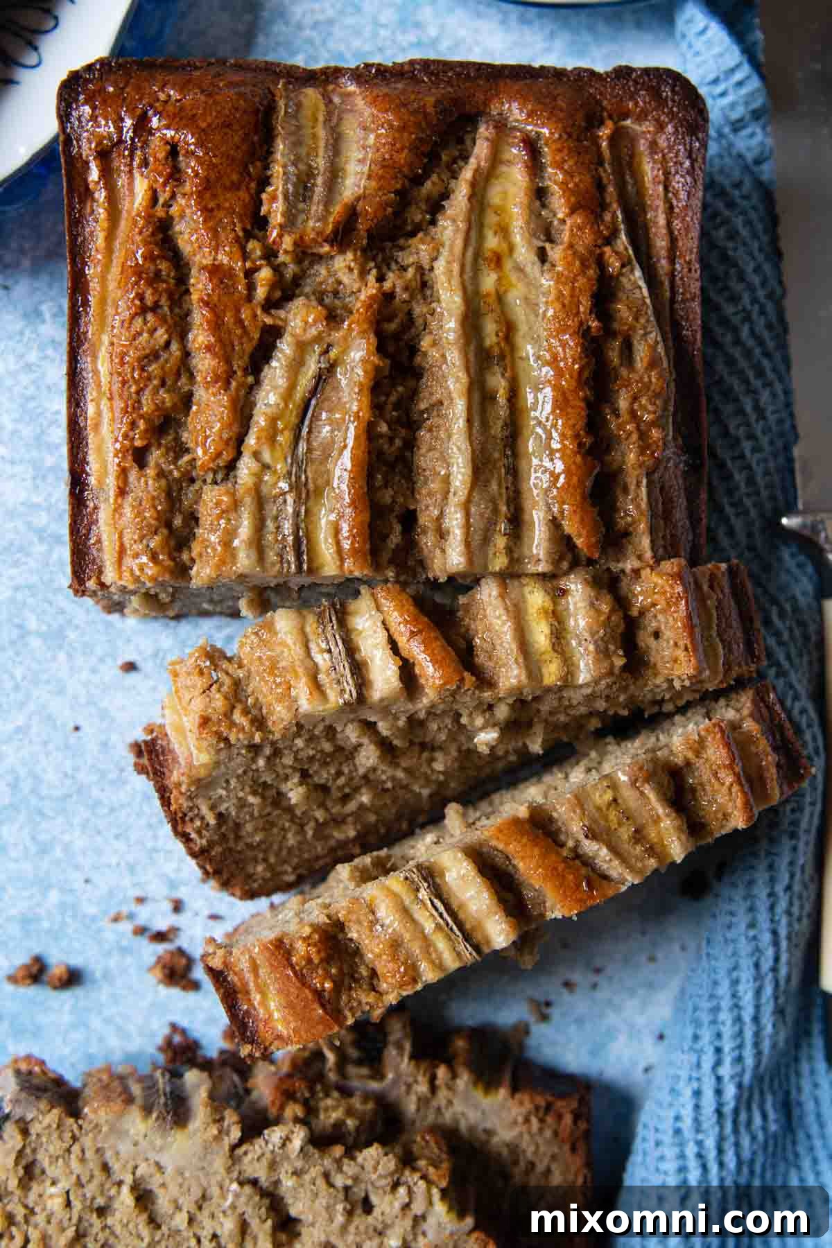 An overhead shot of freshly baked oat flour banana bread, beautifully presented against a soothing blue background.