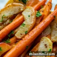 A serving of roasted carrot and apple side dish on a white plate, showcasing its beautiful glaze.