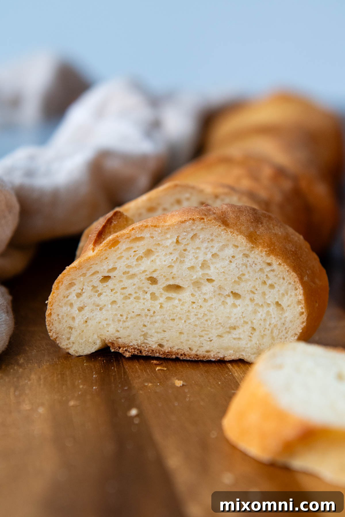 A perfectly baked, crusty gluten-free French bread baguette resting on a wooden cutting board.