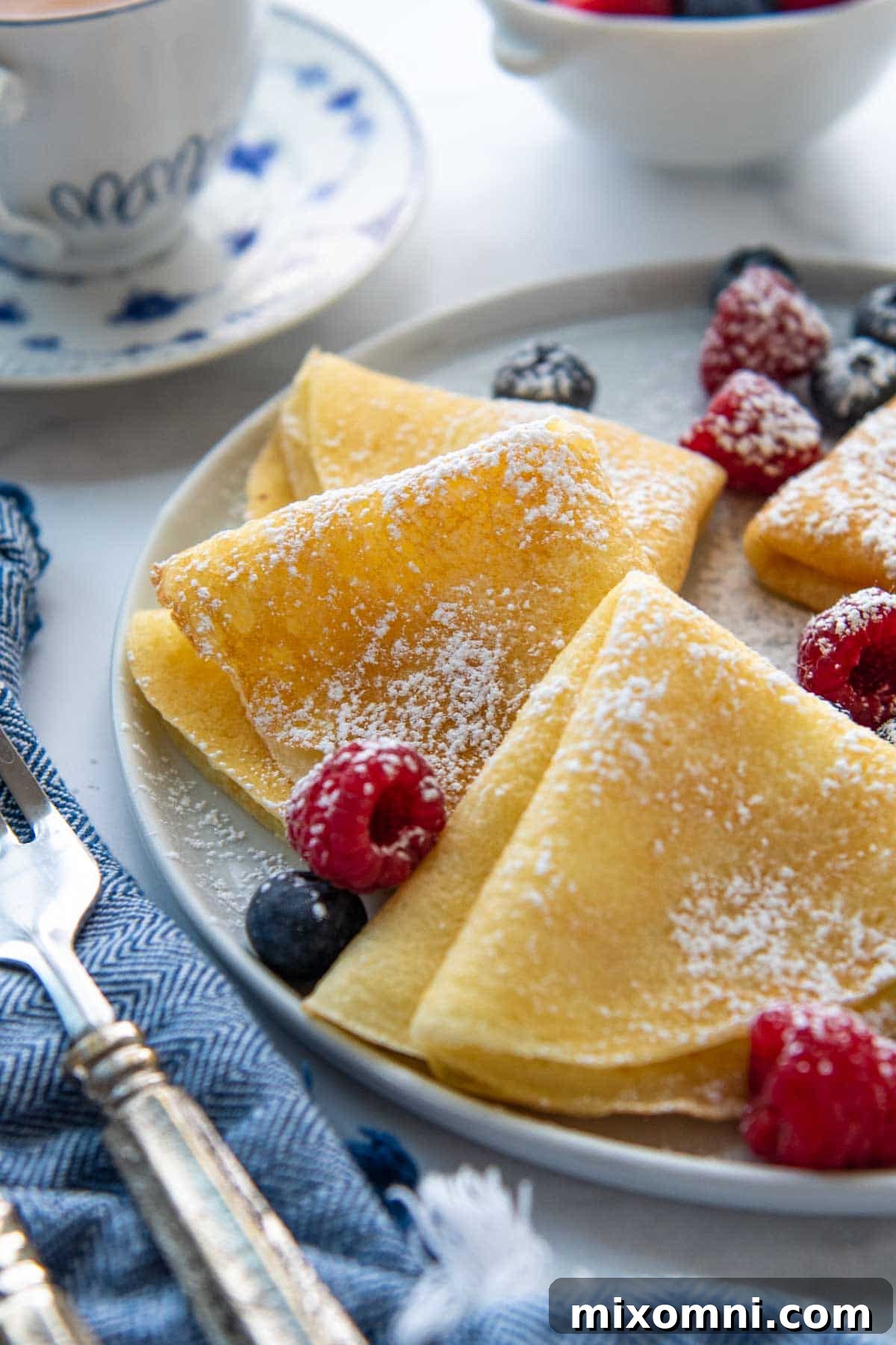 A close-up of beautifully folded gluten-free crepes, surrounded by fresh berries.