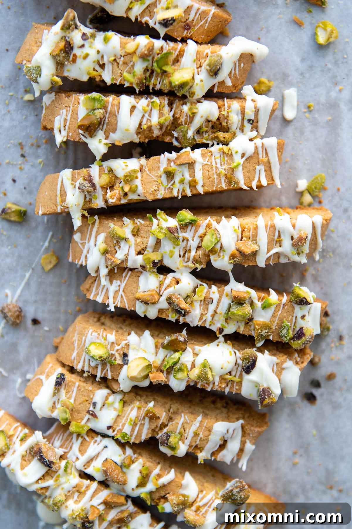 An overhead shot showcasing almond flour biscotti adorned with white chocolate drizzle and vibrant green pistachios, perfectly arranged.