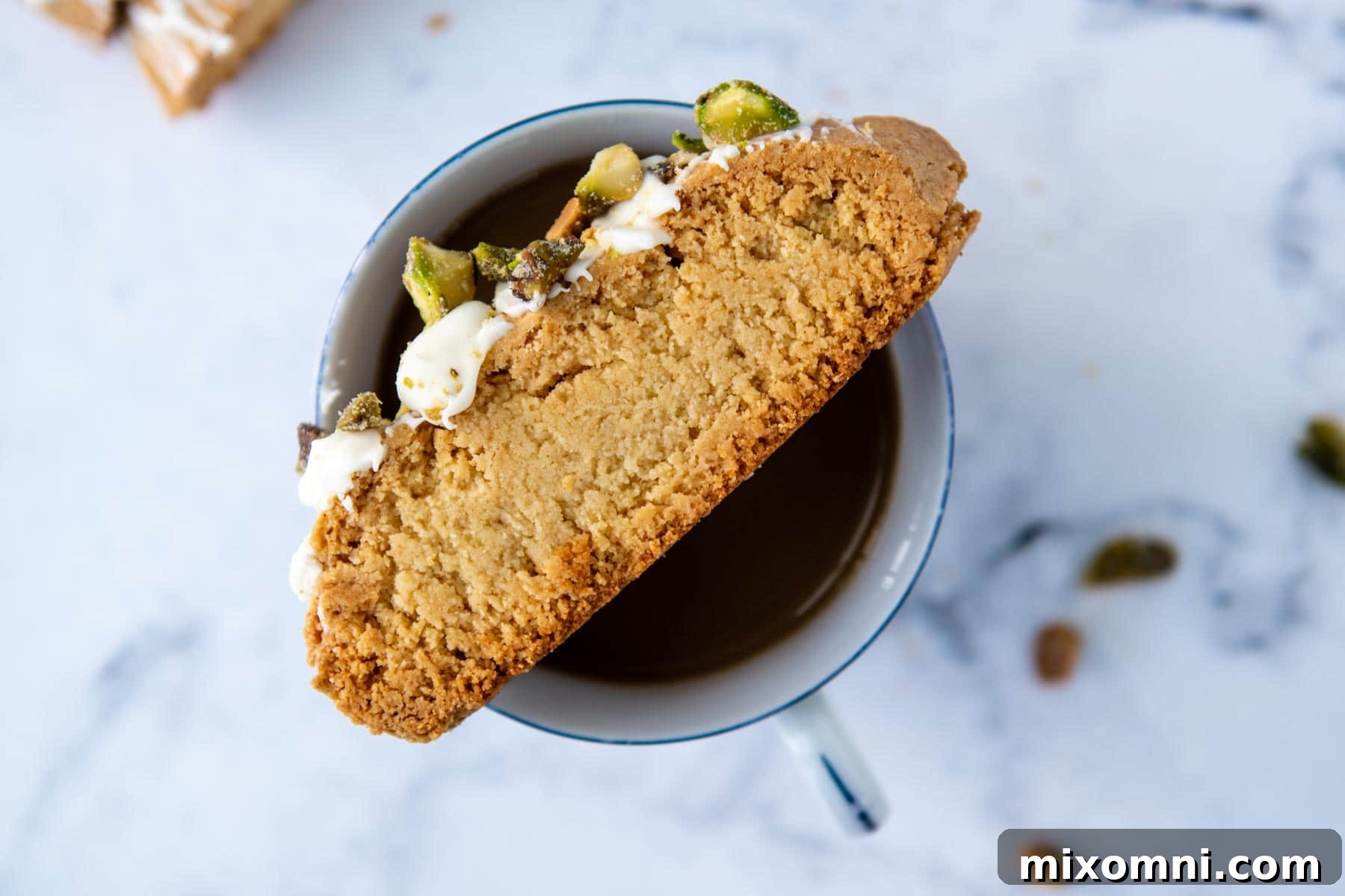 A delicate almond flour biscotti resting gracefully on the rim of a steaming coffee cup, inviting a moment of pure enjoyment.