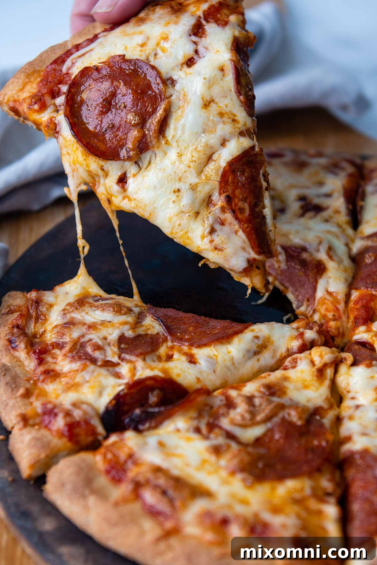 a piece of pizza being pulled from the pan with cheese pulling