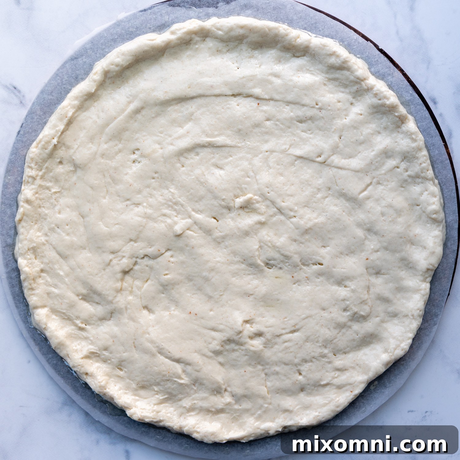 the dough spread out on a piece of parchment.