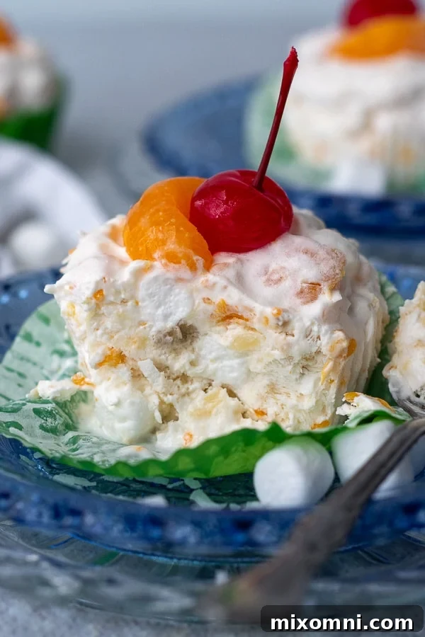 A charming frozen fruit salad cup resting on a blue plate, with a bite taken out and a spoon nearby, inviting you to try more.