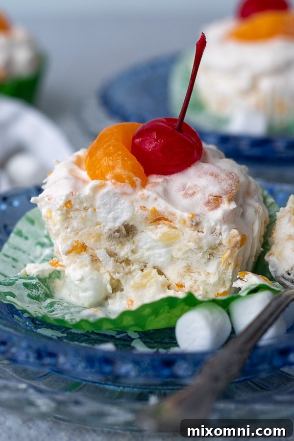 A cup of creamy frozen fruit salad on a blue plate, with a spoon beside it and a bite taken out