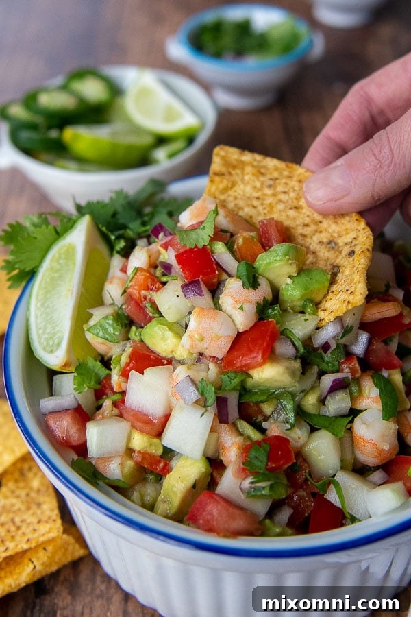 A tortilla chip scooping up a generous portion of vibrant shrimp and avocado salsa