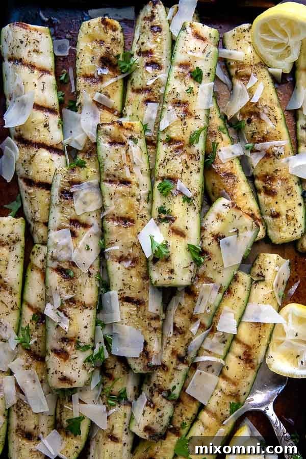 An overhead view of perfectly grilled zucchini and yellow squash on a sheet pan with a serving utensil beneath