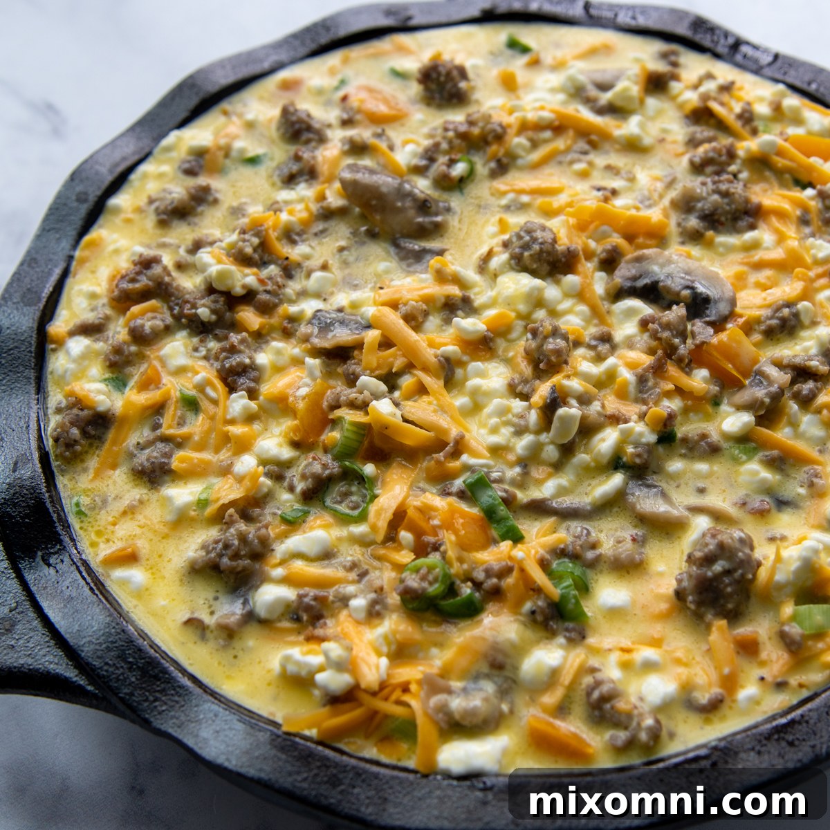 A bowl containing the whisked eggs, cottage cheese, and cheese mixture, ready to be poured over the filling.