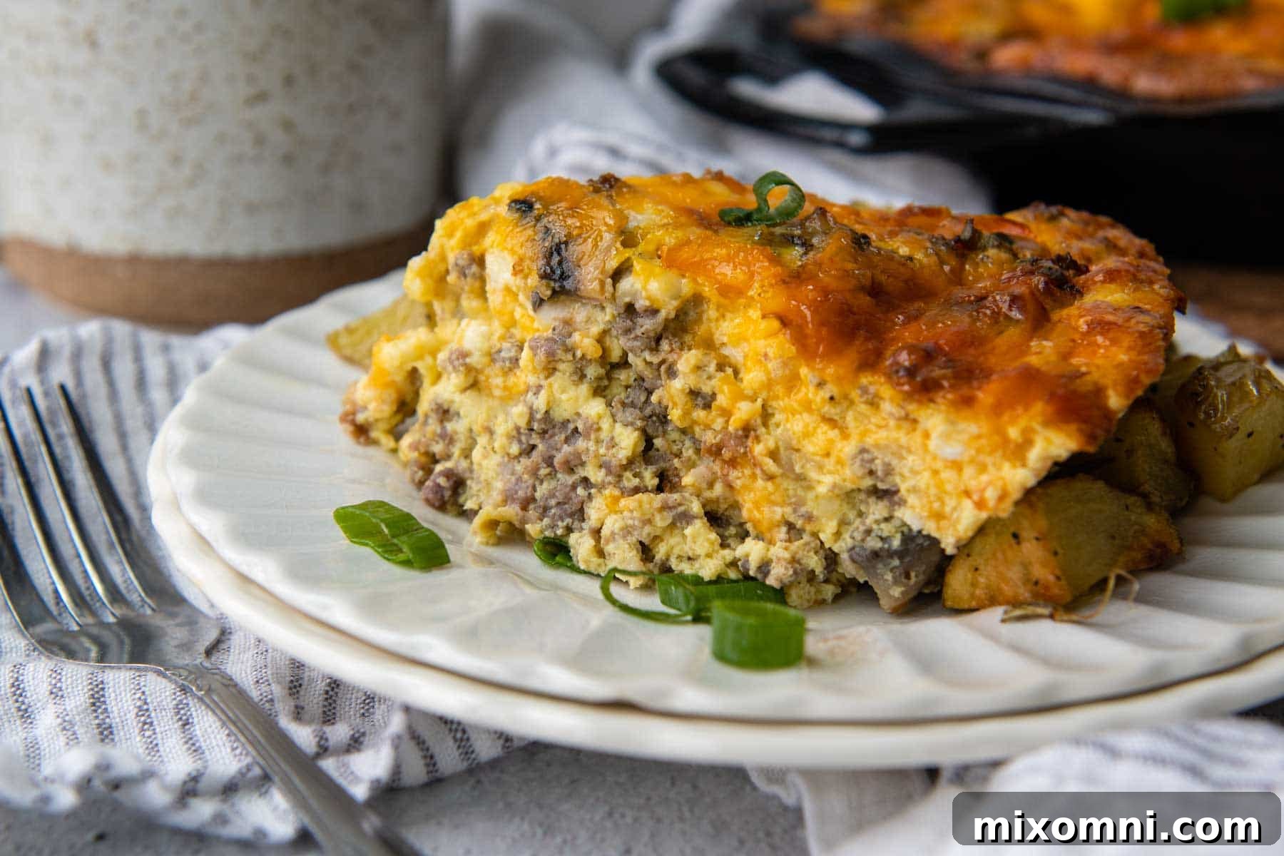 A beautifully plated slice of crustless quiche, garnished with fresh green onions, against a white background.
