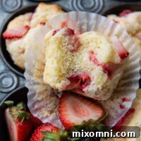a bitten muffins facing up towards the camera resting on a paper liner.