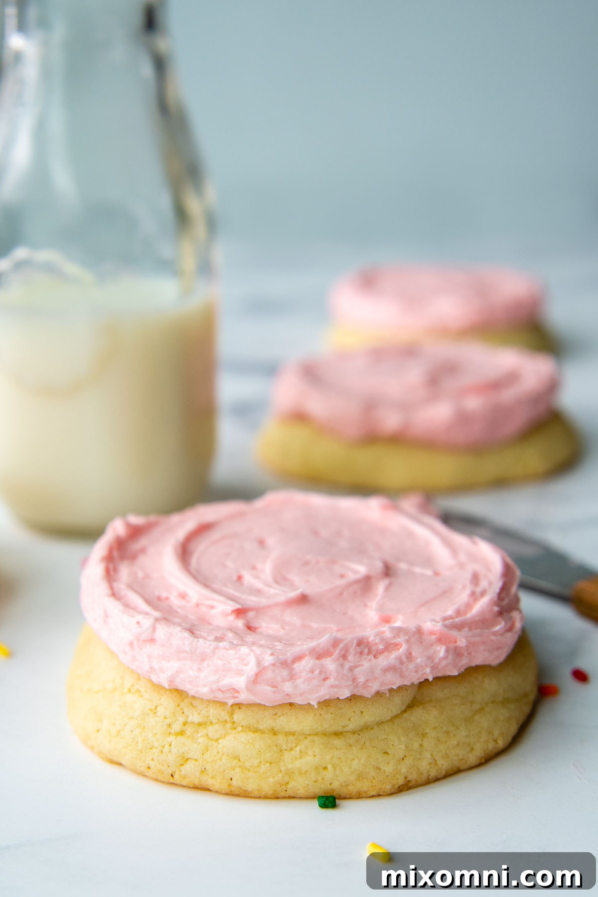 A delectable close-up, straight-on shot of a perfectly frosted sugar cookie with fluffy pink buttercream.