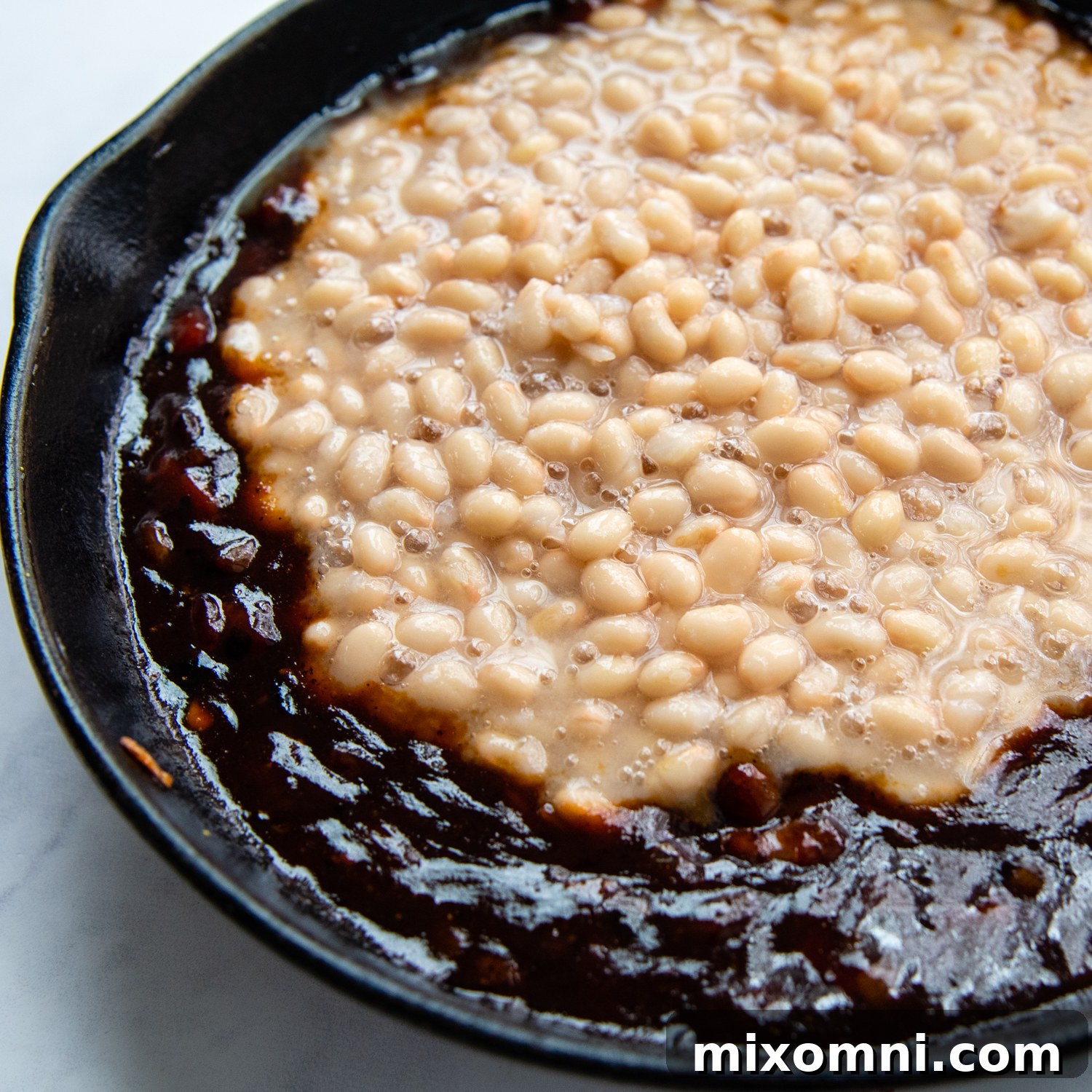 canned beans being added to the sauce.