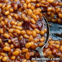 a close up of an antique spoon scooping baked beans.