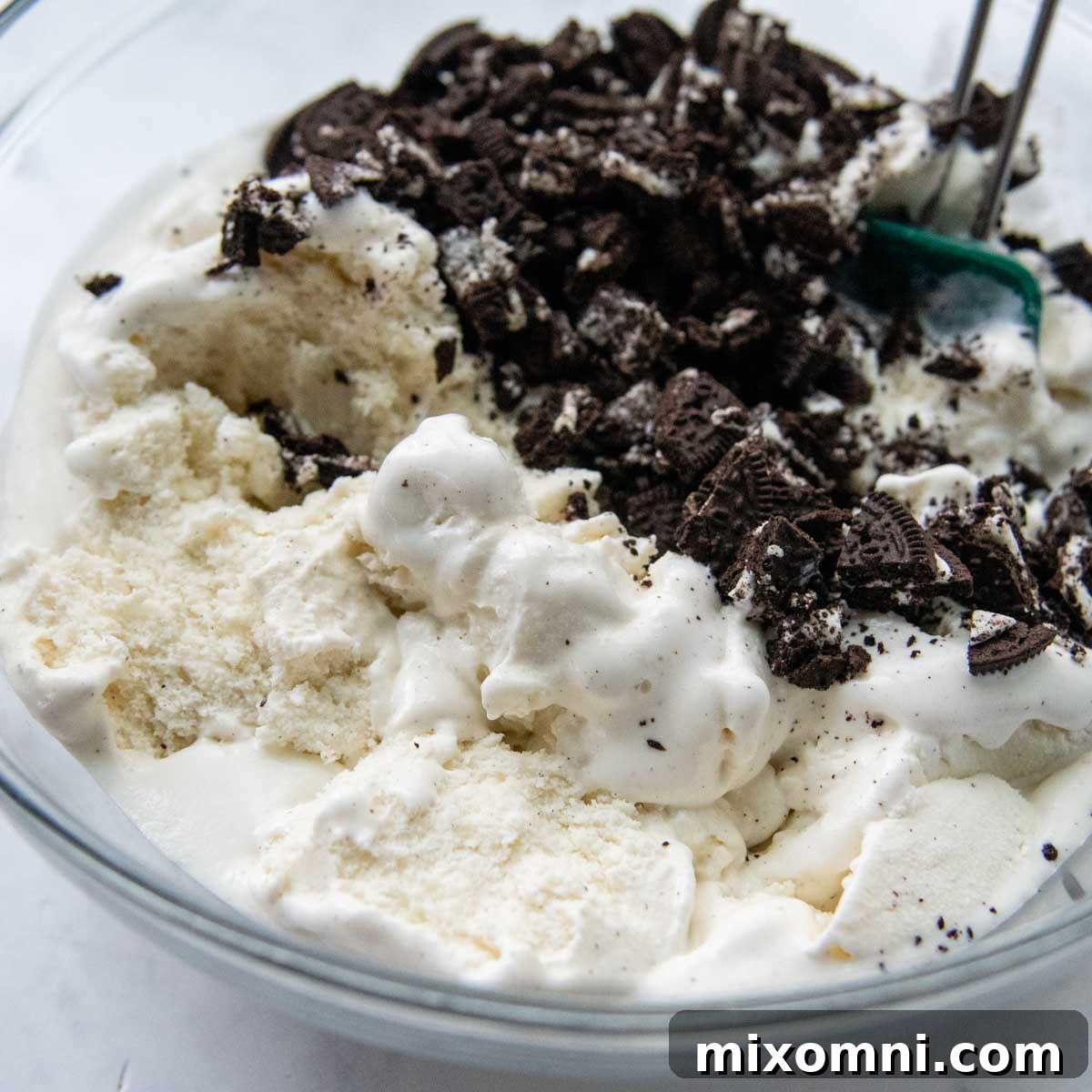 Gluten-free cookie crumbs mixed with softened ice cream, ready for freezing.