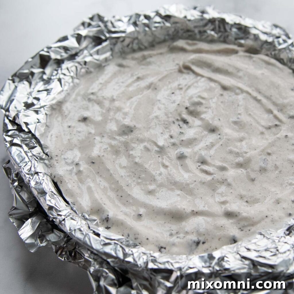 Softened ice cream spread evenly in a cake pan, prepared for freezing.