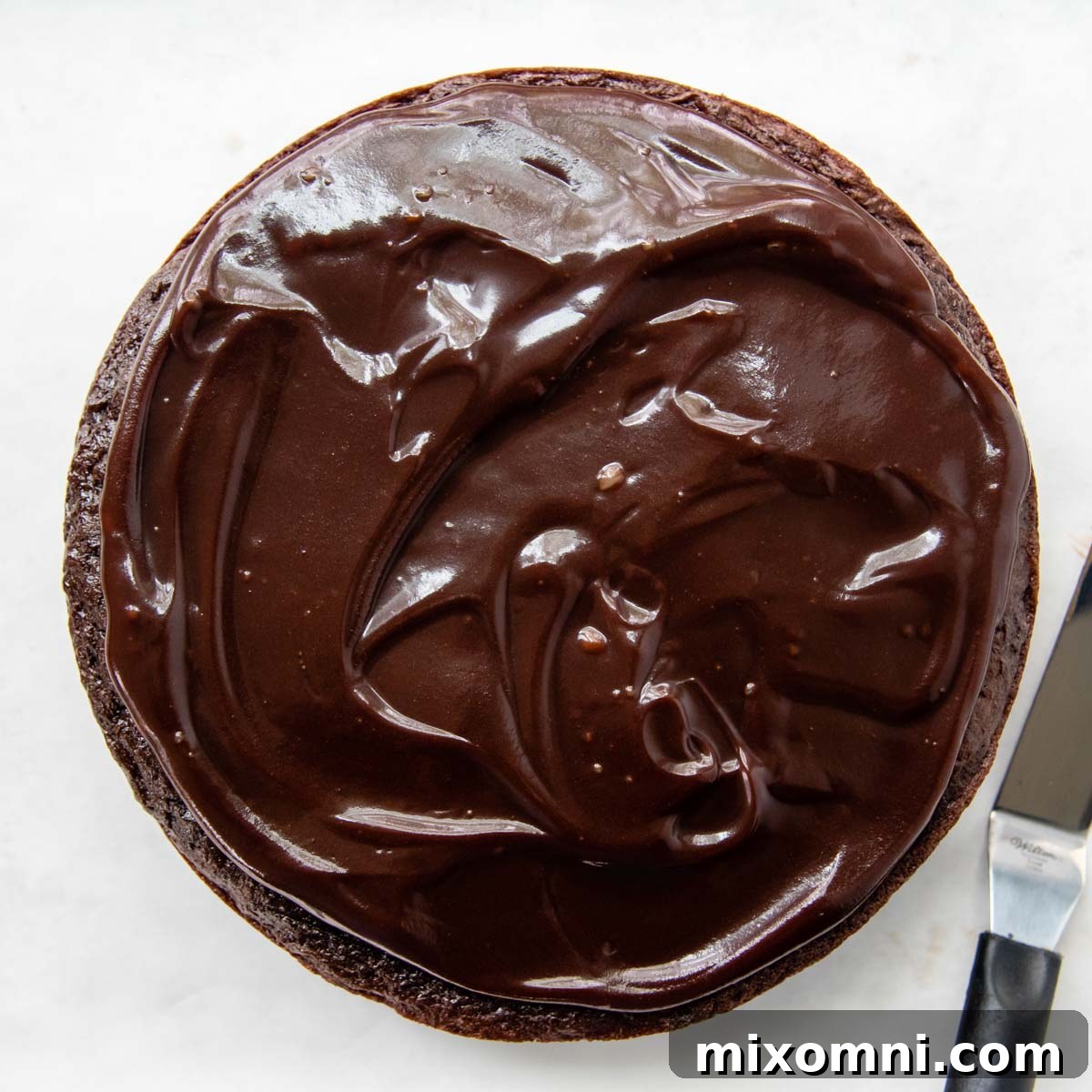 A smooth layer of hot fudge spread over the chocolate cake.