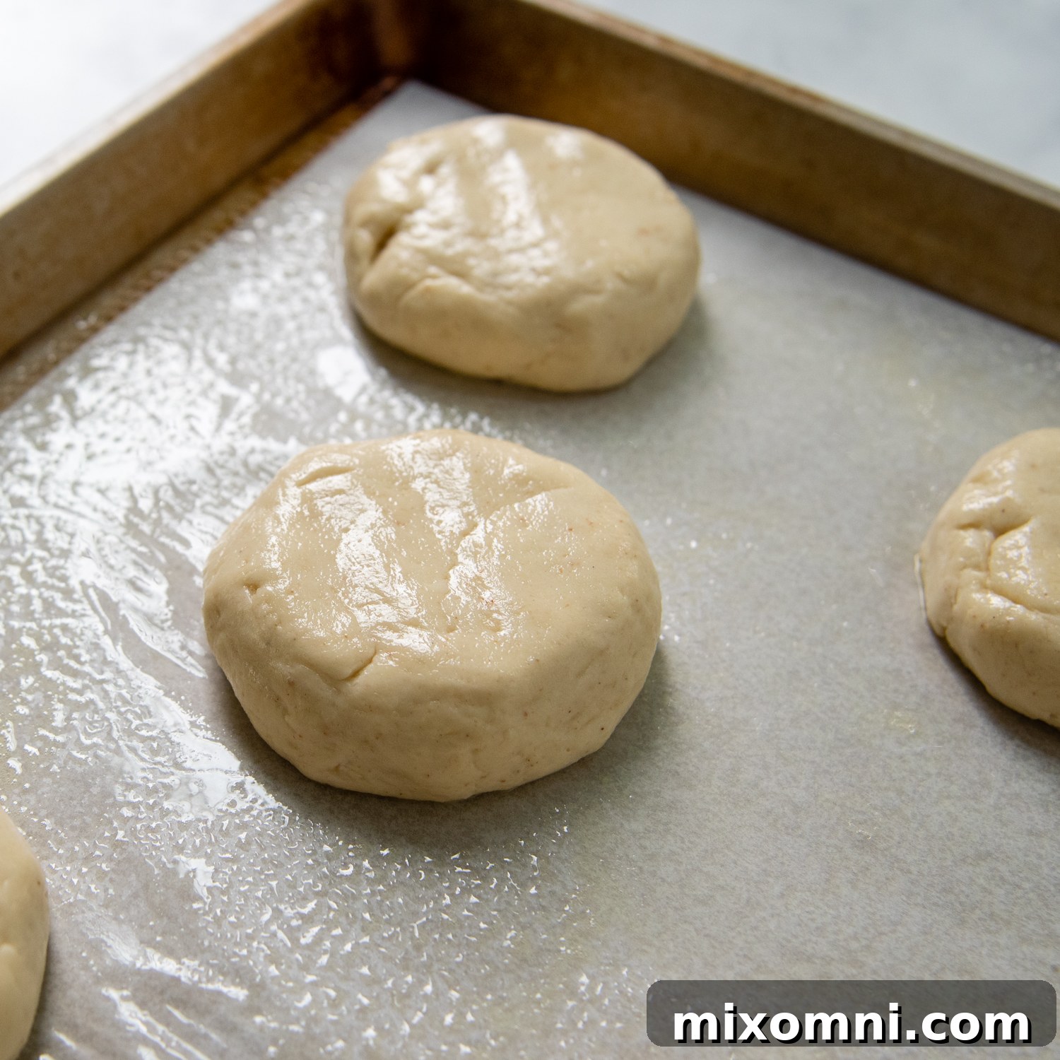 the buns flattened down slightly before sitting aside to rise.