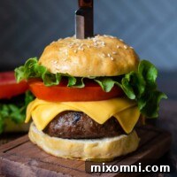 a straight on shot of an assembled burger with a knife stabbed into the top.