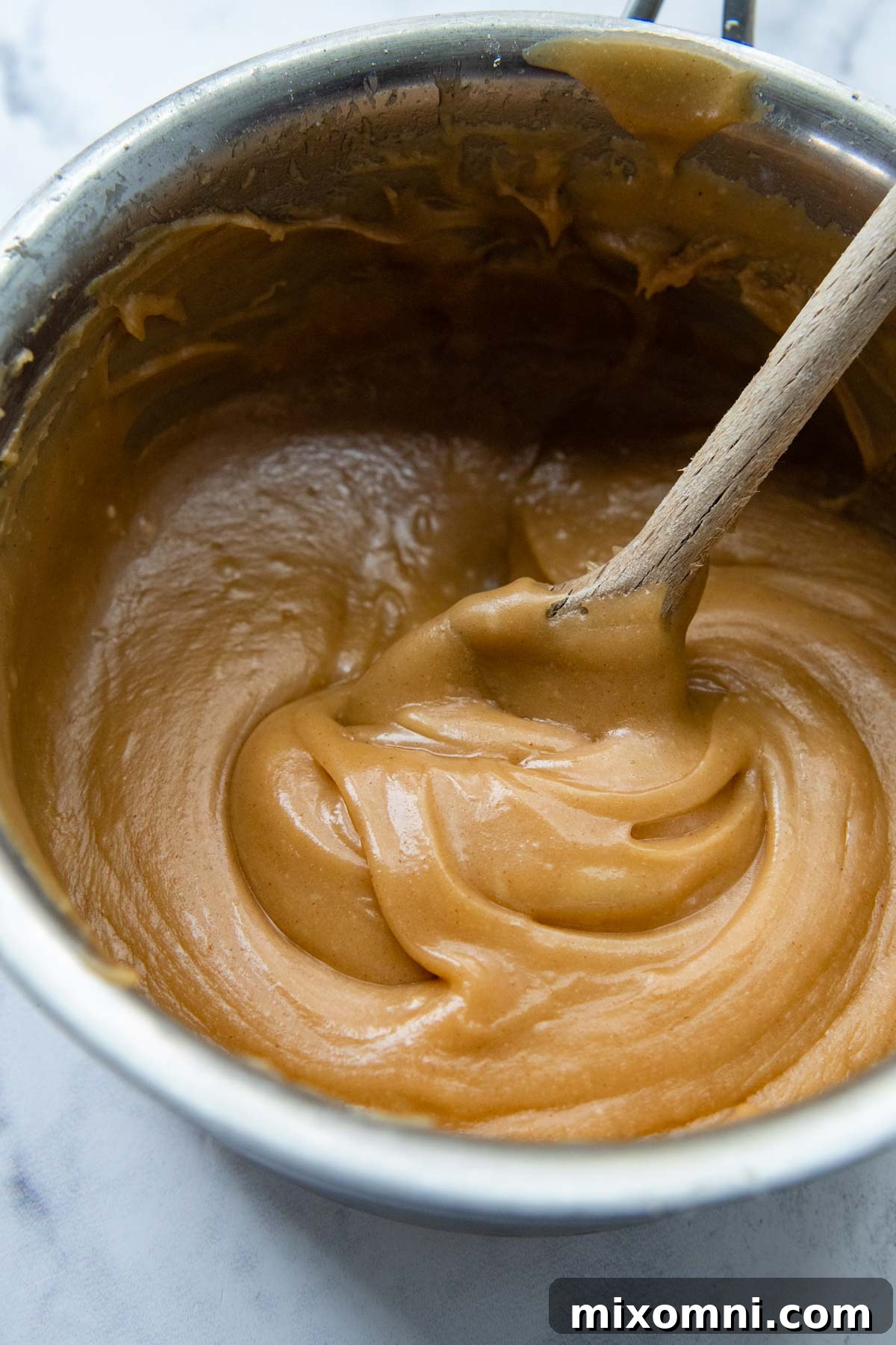 A saucepan on the stove containing freshly mixed peanut butter glaze, smooth and ready to use.