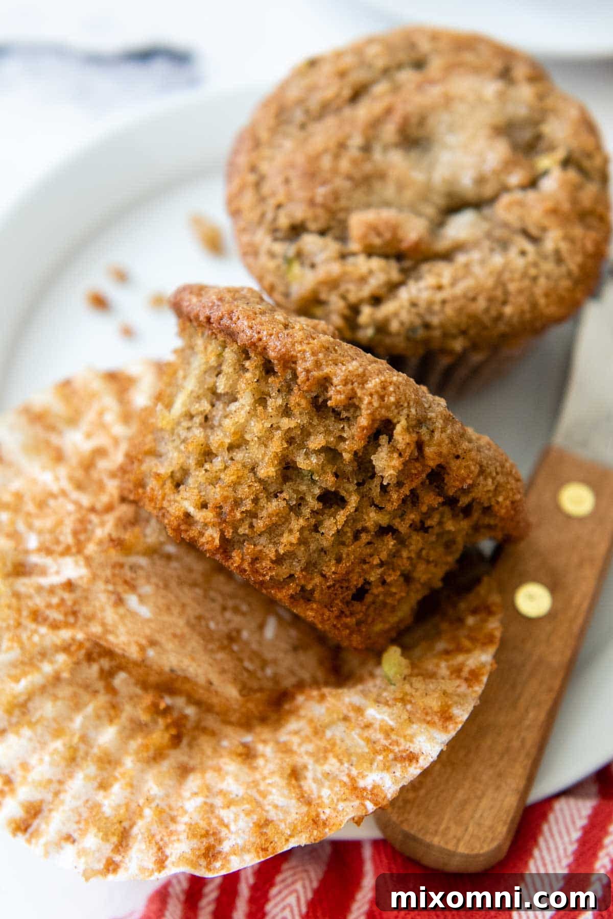 A perfectly baked almond flour zucchini muffin with its paper liner removed, showcasing its tender crumb and golden-brown top.