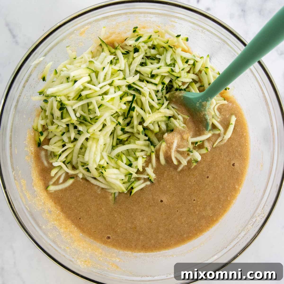 Muffin batter with shredded zucchini visible, ready to be scooped into a muffin pan.