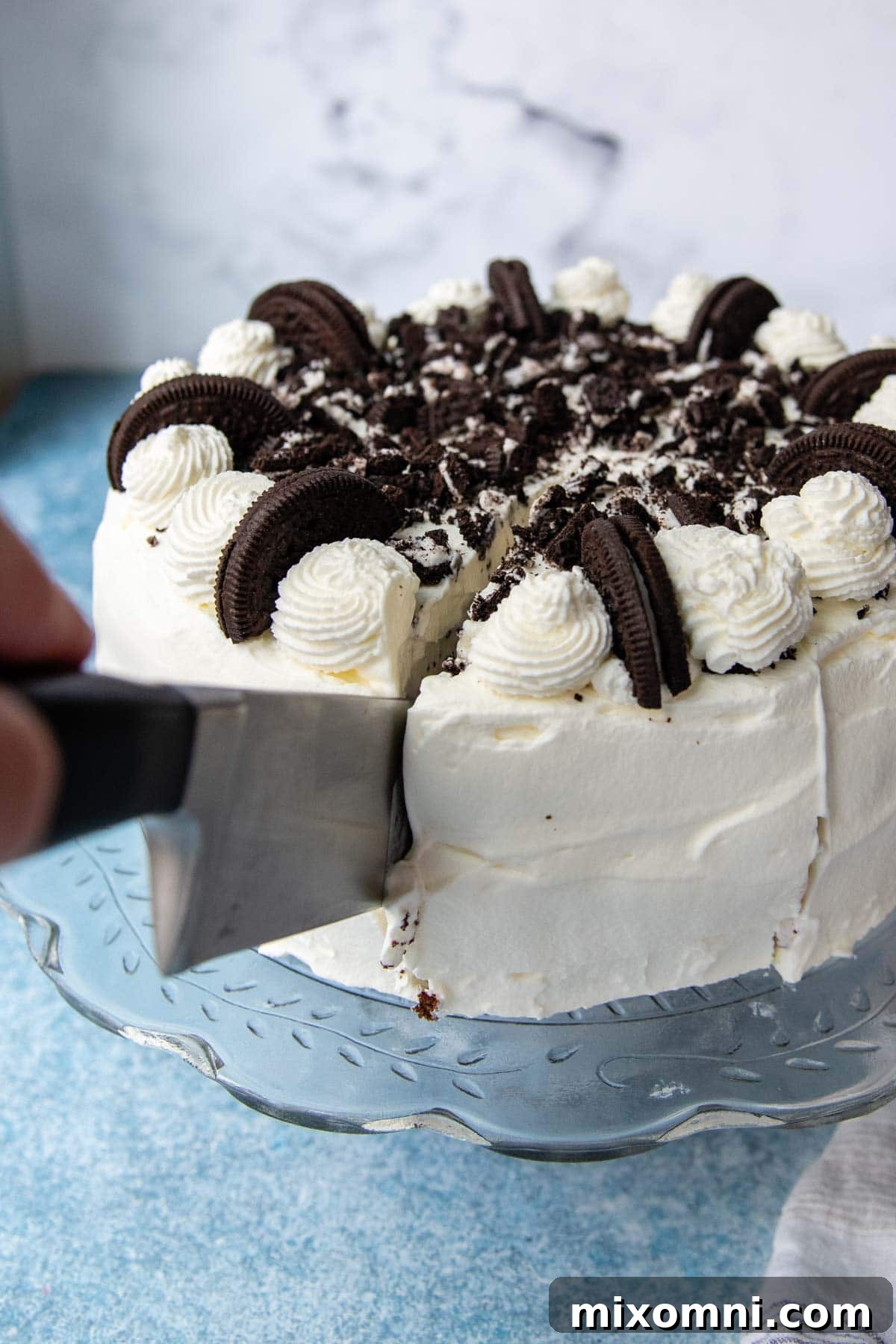 A large, sharp chef's knife effortlessly slicing into an ice cream cake, showing the clean cut through the frozen layers.