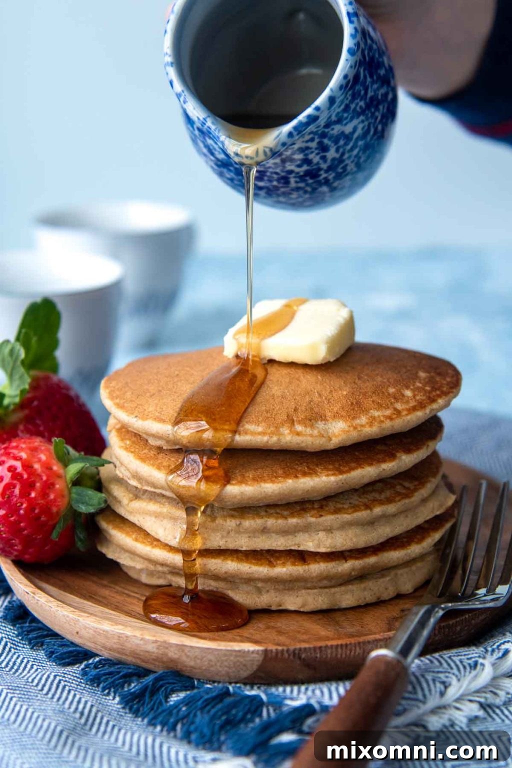 syrup being poured on uncut flourless pancakes stack