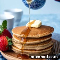 syrup being poured on uncut flourless pancakes stack