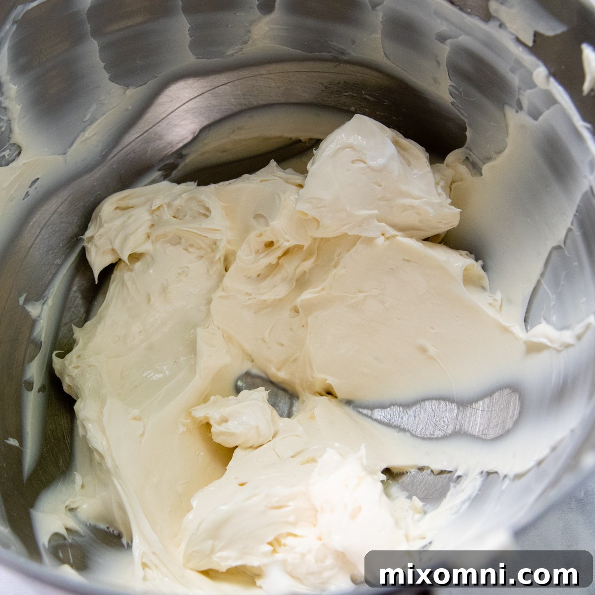 The smooth and creamy cheesecake filling mixture in a large stainless steel bowl, ready for the next step.