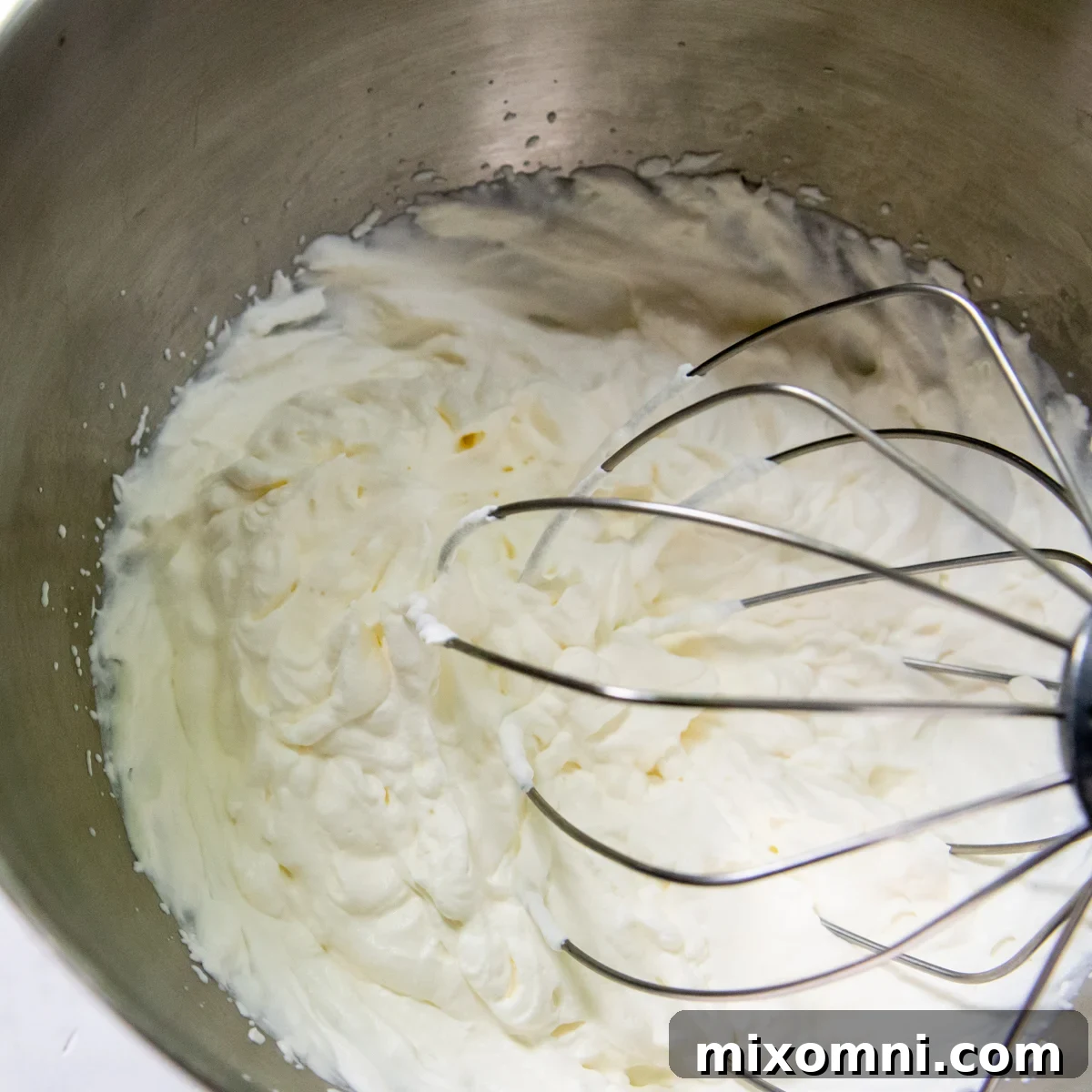 Heavy cream being beaten to stiff peaks, showing the perfect fluffy consistency.
