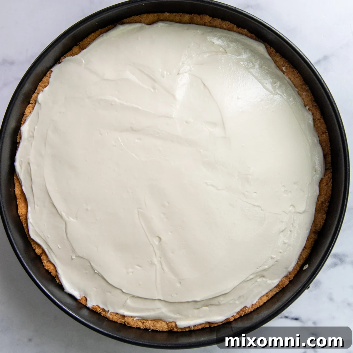 The smooth cheesecake filling spread evenly into the prepared crust, ready for chilling.