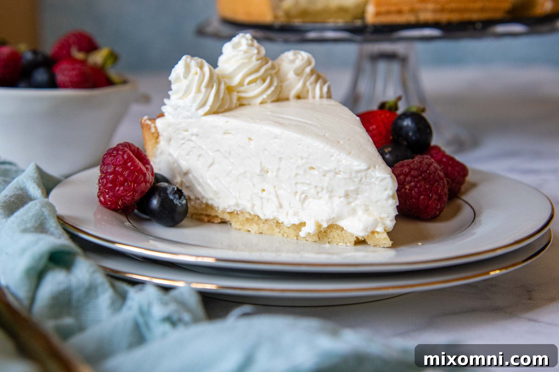 A beautiful slice of gluten-free cheesecake on a white plate, garnished with a handful of fresh berries.