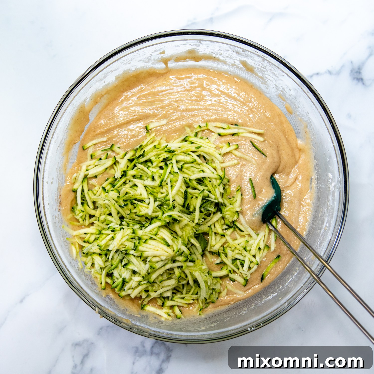 The bread batter in a mixing bowl with freshly grated zucchini evenly mixed in, ready for blueberries.