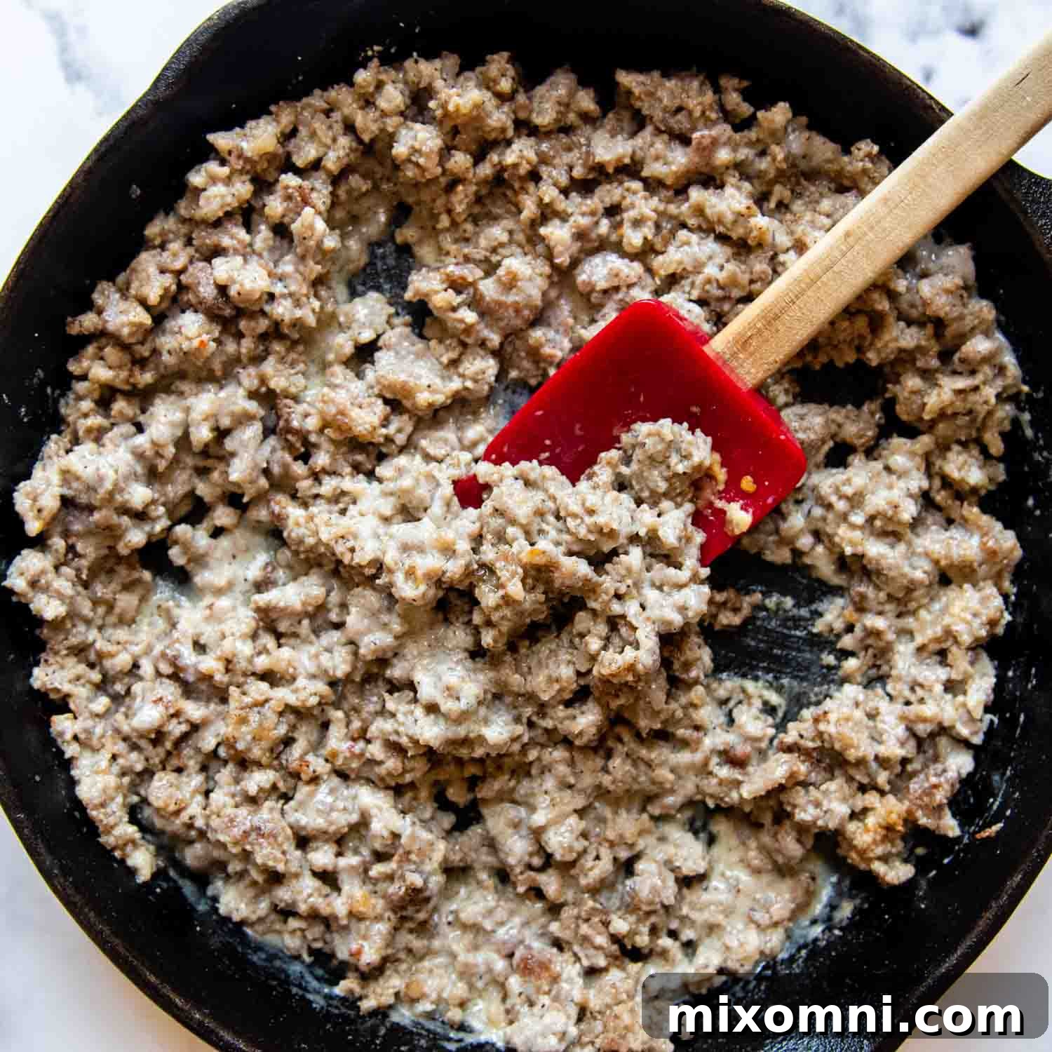 sausage with a thick white sauce beginning to form in the skillet.