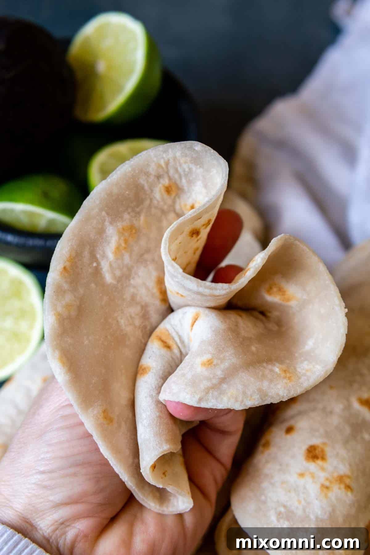 a flour tortilla scrunched up in a hand.